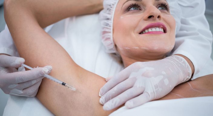 Close-up of doctor injecting woman on her arm pits