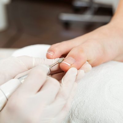 Portrait of young woman doing pedicure in salon. Beauty concept.